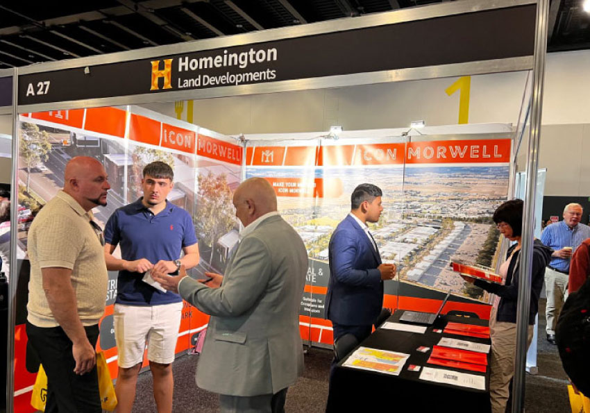 Homeington Land Developments' stall at the 33rd Australian Property Expo 2024 in Sydney, with team members talking with visitors and showing the Icon Morwell Innovation Park.